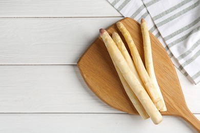 Photo of Raw asparagus spears on white wooden table, top view. Space for text