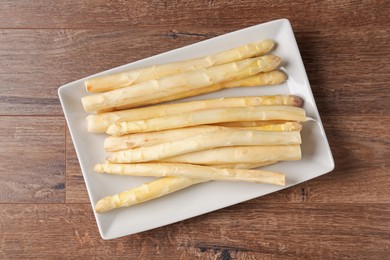 Photo of Raw white asparagus spears on wooden table, top view