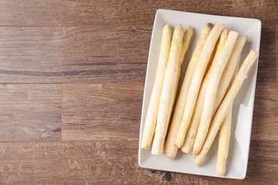 Photo of Raw white asparagus spears on wooden table, top view. Space for text