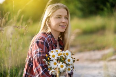 Photo of Beautiful woman with bouquet of wildflowers in meadow