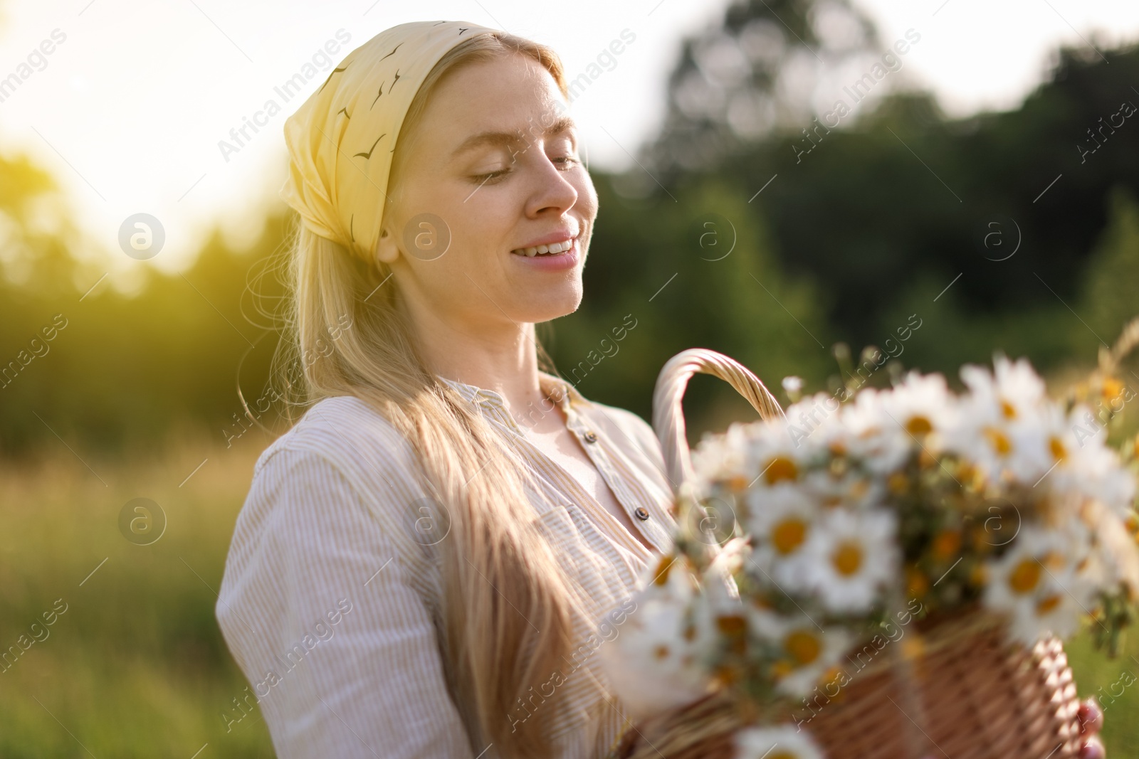 Happy woman with basket full of beautiful wildflowers outdoors Photo of Happy woman with basket full of beautiful wildflowers outdoors