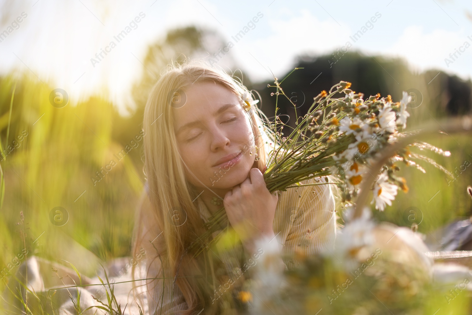 Beautiful woman with wildflowers in meadow on sunny day Photo of Beautiful woman with wildflowers in meadow on sunny day