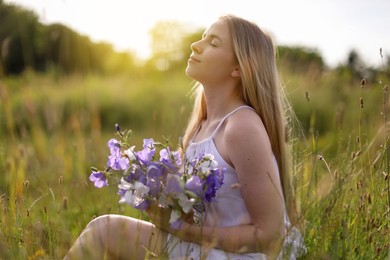 Photo of Beautiful woman with bouquet of wildflowers enjoying sunny day in meadow
