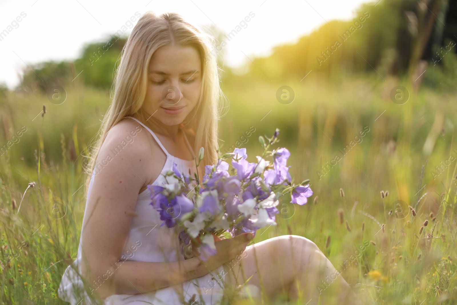 Beautiful woman with bouquet of wildflowers enjoying sunny day in meadow. Space for text Photo of Beautiful woman with bouquet of wildflowers enjoying sunny day in meadow. Space for text