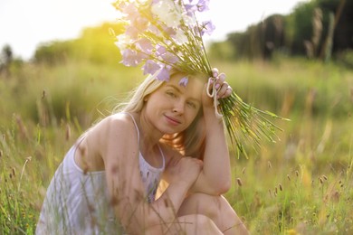 Photo of Beautiful woman with bouquet of wildflowers enjoying sunny day in meadow
