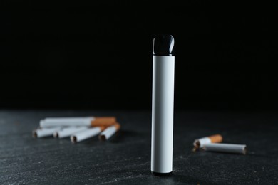 Photo of Electronic smoking device and cigarettes on black table