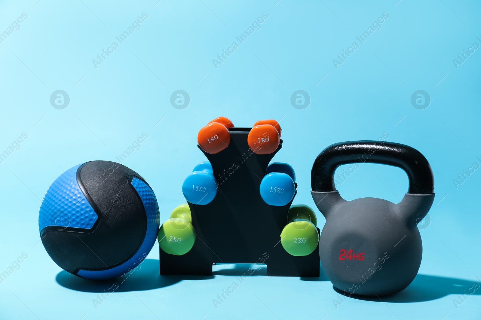 Medicine ball, dumbbells and kettlebell on light blue background Photo of Medicine ball, dumbbells and kettlebell on light blue background