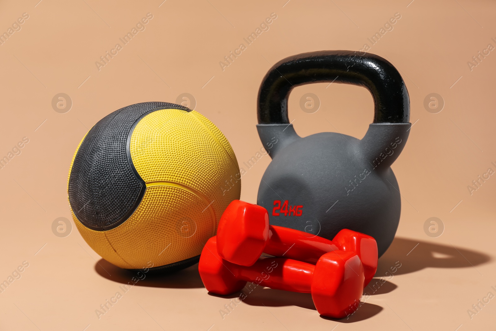 Medicine ball, dumbbells and kettlebell on beige background Photo of Medicine ball, dumbbells and kettlebell on beige background