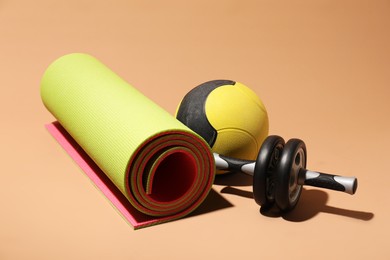 Photo of Medicine ball, fitness mat and ab wheel on beige background