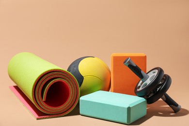 Photo of Medicine ball, foam blocks, ab wheel and fitness mat on beige background