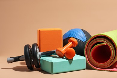 Photo of Medicine ball, dumbbells, foam blocks, ab wheel and fitness mat on beige background