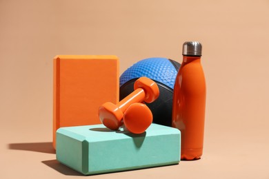 Photo of Medicine ball, dumbbells, foam blocks and water bottle on beige background