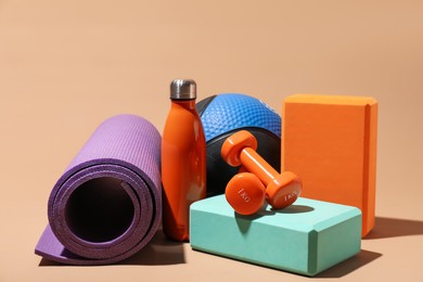 Photo of Medicine ball, fitness mat, dumbbells, foam blocks and water bottle on beige background