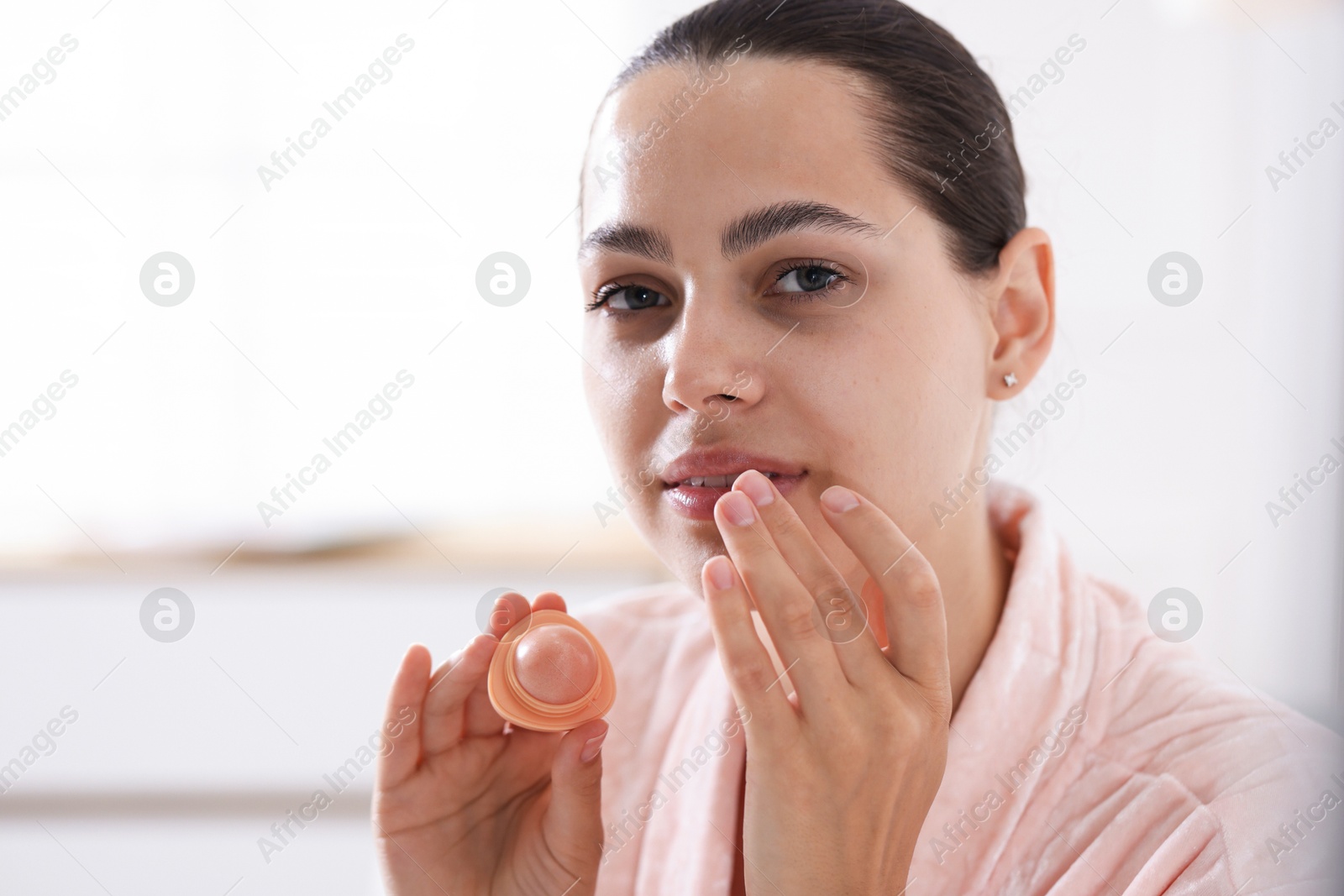 Young woman with lip balm at home, space for text Photo of Young woman with lip balm at home, space for text