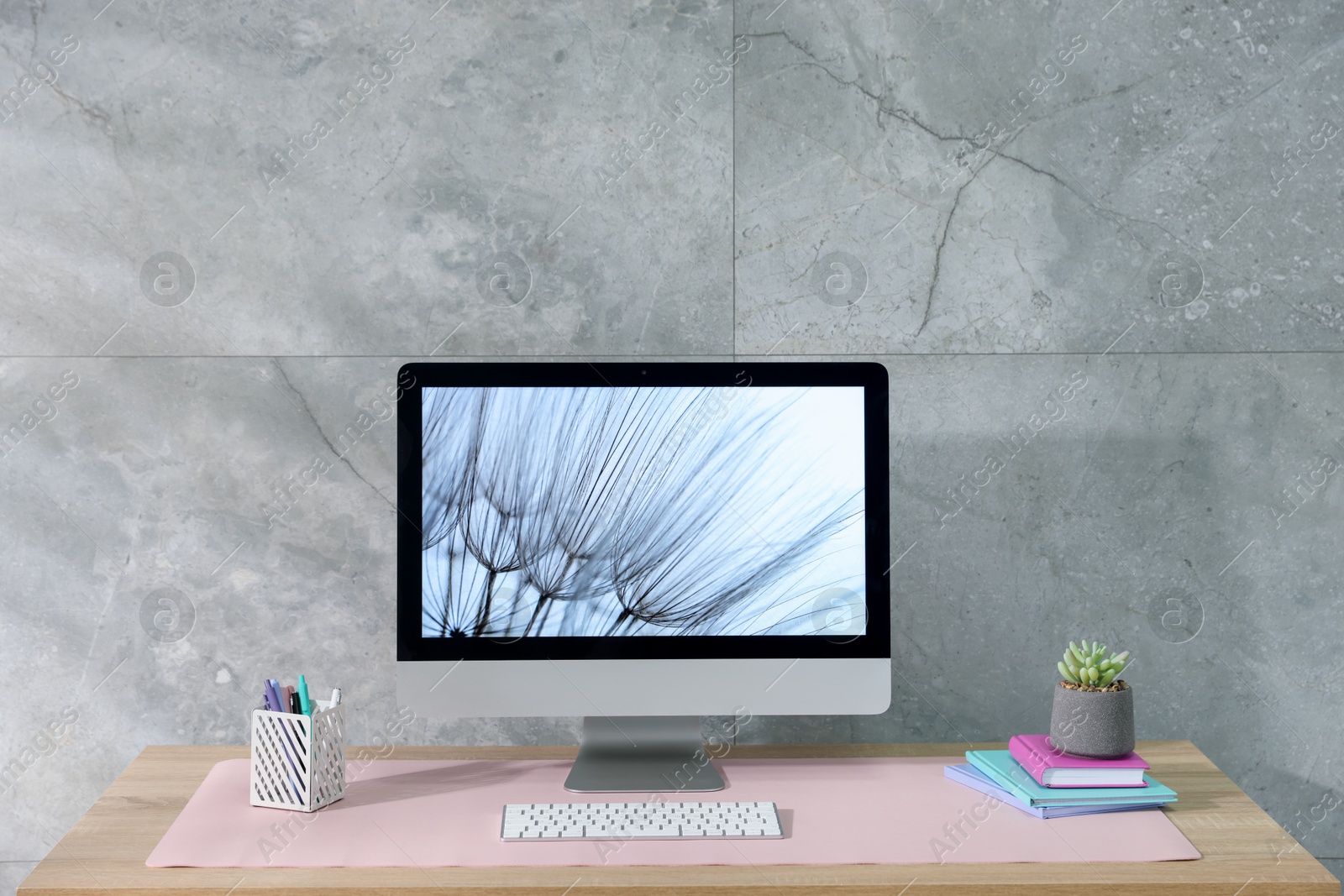 Photo of Stylish workplace with computer and pink mousepad on wooden table indoors