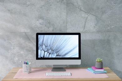 Photo of Stylish workplace with computer and pink mousepad on wooden table indoors