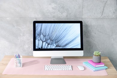 Photo of Stylish workplace with computer and pink mousepad on wooden table indoors