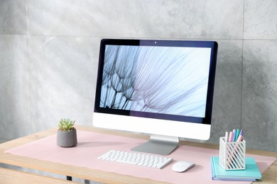 Photo of Stylish workplace with computer and pink mousepad on wooden table indoors
