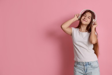Photo of Teenage girl in headphones on pink background, space for text
