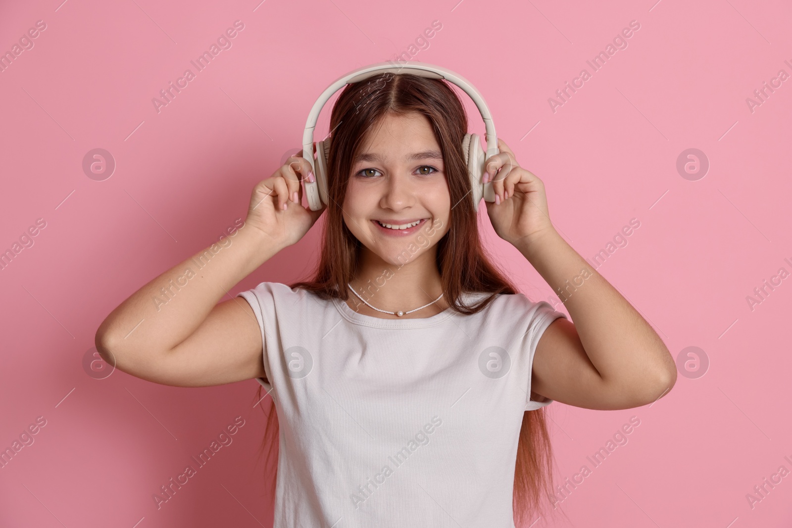 Teenage girl in headphones on pink background Photo of Teenage girl in headphones on pink background