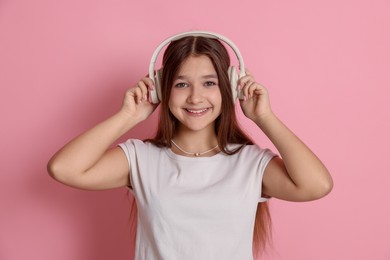 Photo of Teenage girl in headphones on pink background