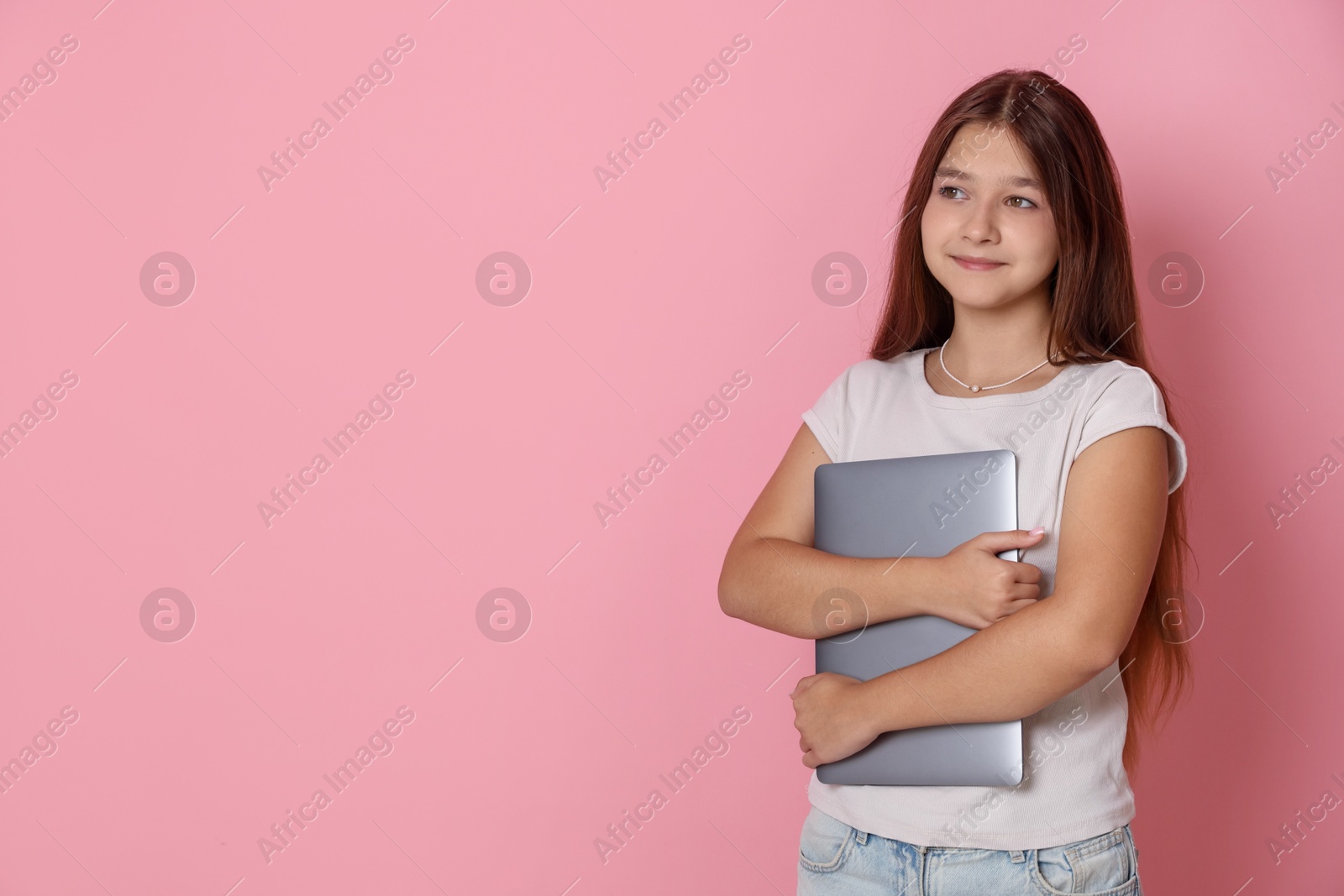 Teenage girl with laptop on pink background, space for text Photo of Teenage girl with laptop on pink background, space for text