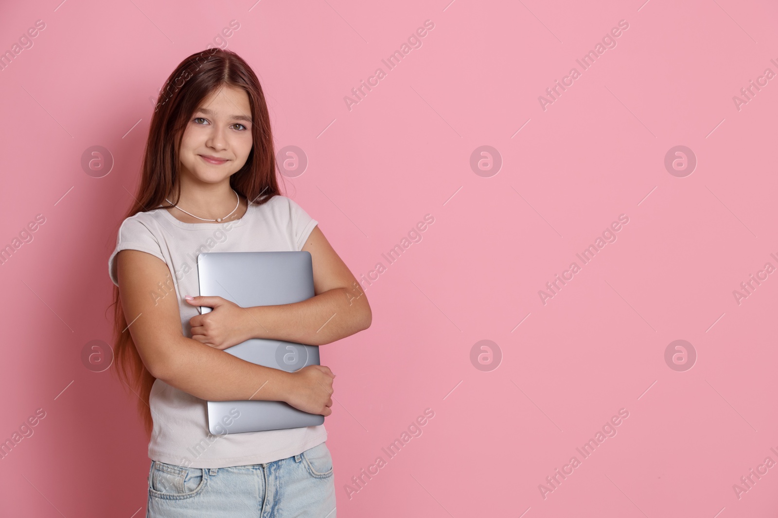 Teenage girl with laptop on pink background, space for text Photo of Teenage girl with laptop on pink background, space for text