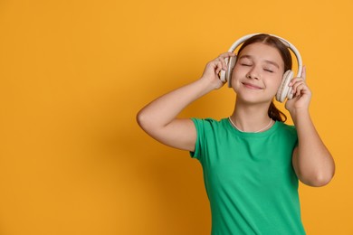 Photo of Teenage girl in headphones on orange background, space for text