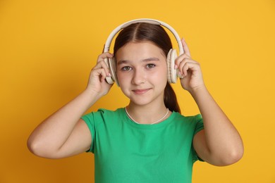 Photo of Teenage girl in headphones on orange background