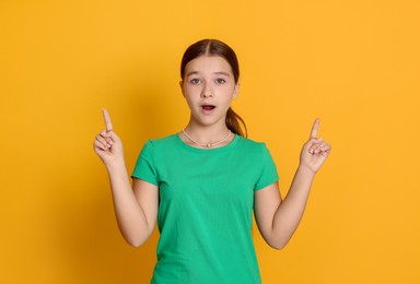 Photo of Teenage girl pointing at something on orange background