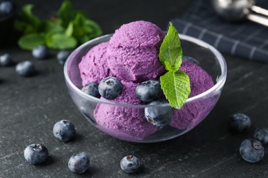 Photo of Tasty sorbet with blueberries and mint on black table, closeup