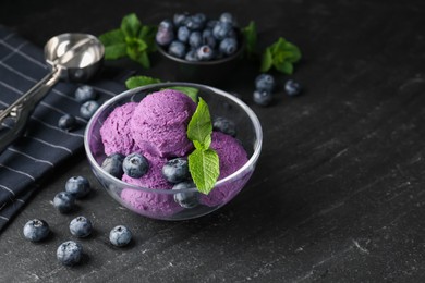 Photo of Tasty sorbet with blueberries and mint on black table, closeup. Space for text