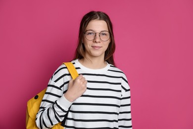 Photo of Teenage girl in glasses with backpack on crimson background, space for text