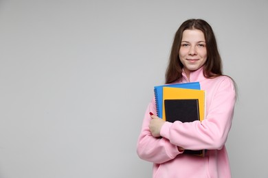 Photo of Teenage girl with notebooks on light grey background, space for text