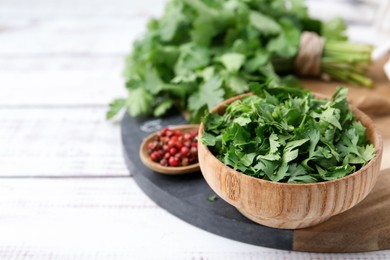 Photo of Fresh green cilantro and peppercorns on white wooden table, closeup. Space for text