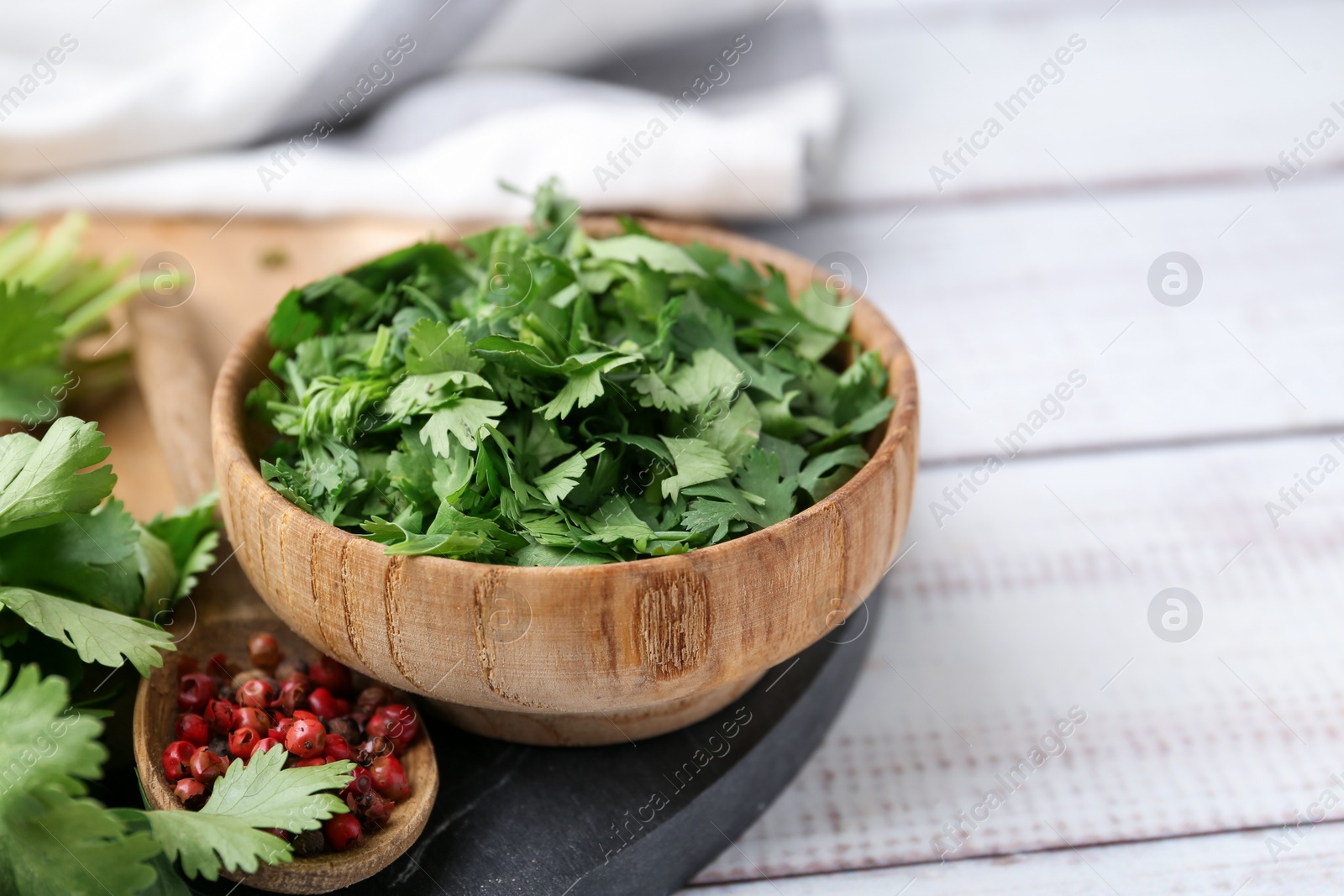Photo of Fresh green cilantro and peppercorns on white wooden table, closeup. Space for text