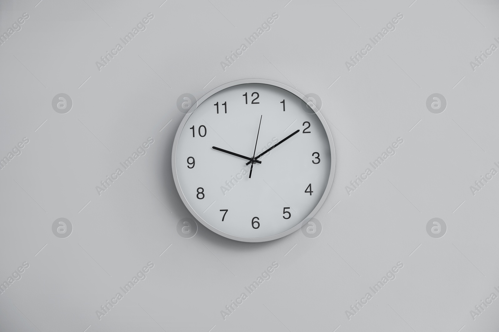 Stylish round clock on white wall indoors Photo of Stylish round clock on white wall indoors