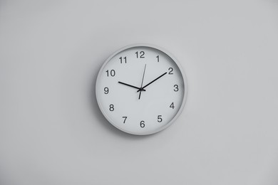Photo of Stylish round clock on white wall indoors