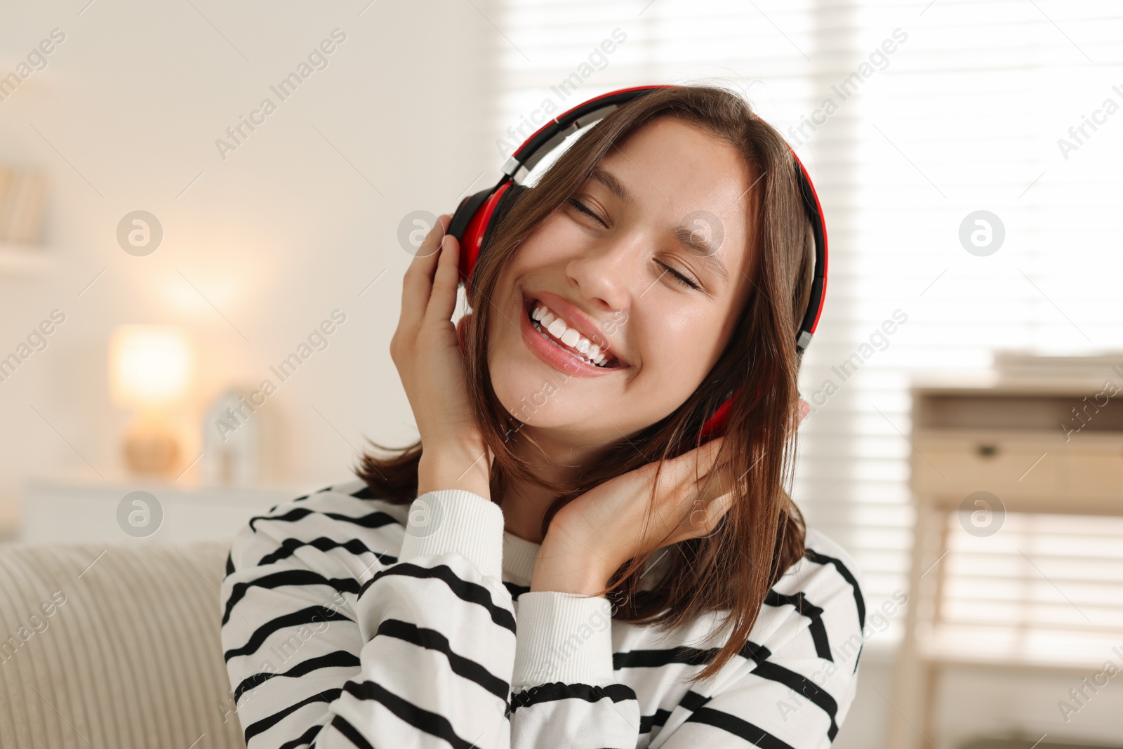 Photo of Portrait of smiling teenage girl in headphones at home