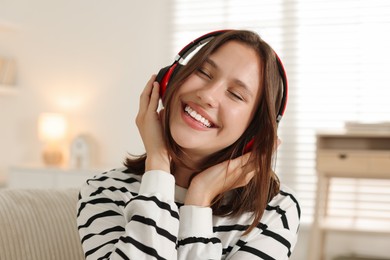 Photo of Portrait of smiling teenage girl in headphones at home