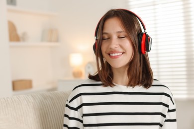 Photo of Smiling teenage girl in headphones at home. Space for text