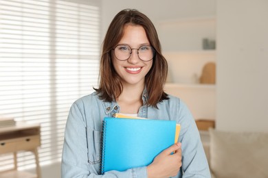 Photo of Smiling teenage girl with notepads at home