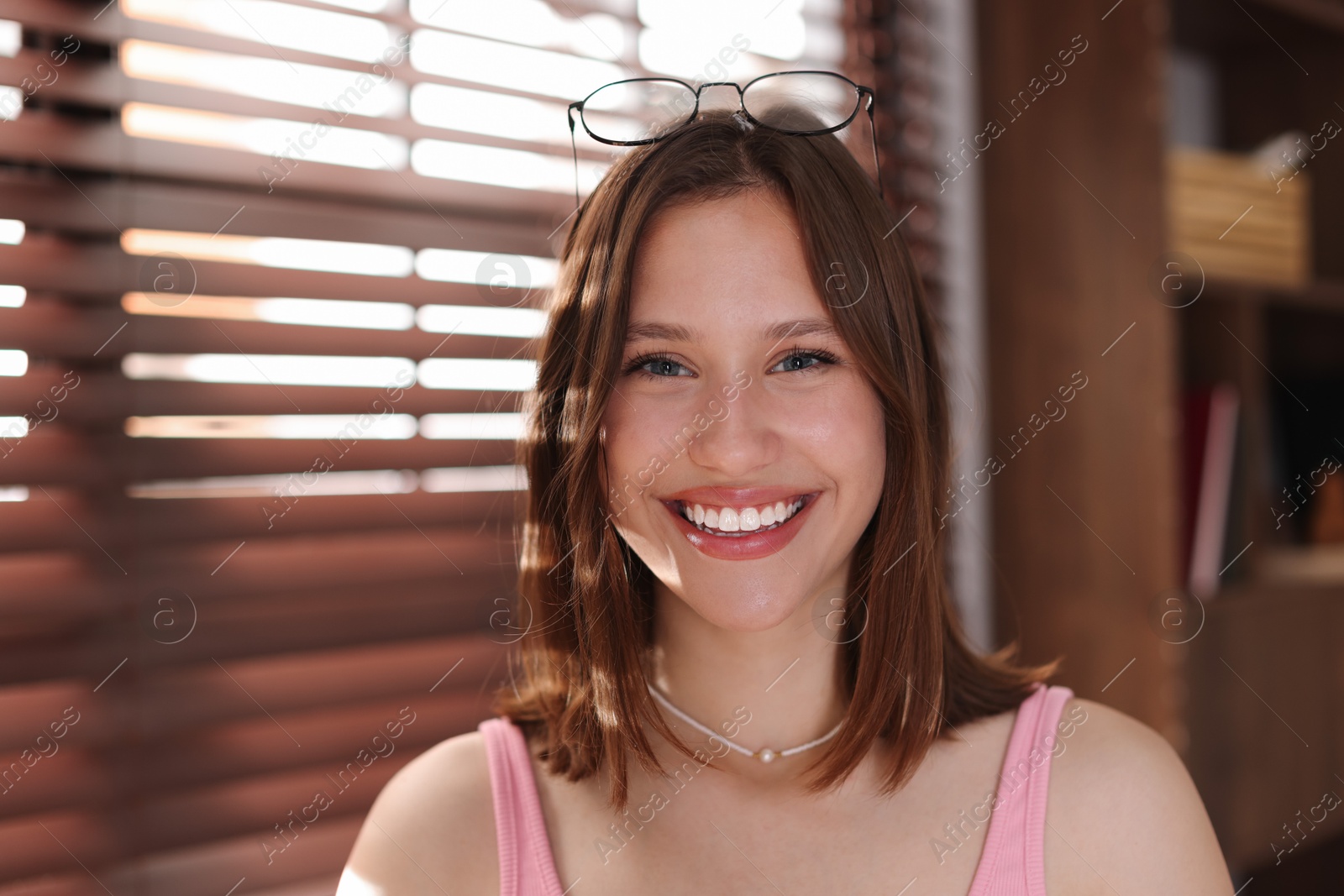Photo of Portrait of smiling teenage girl with glasses at home