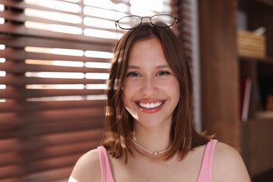 Photo of Portrait of smiling teenage girl with glasses at home