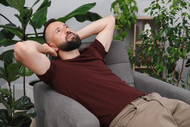 Photo of Harmony. Man relaxing in comfortable armchair at home