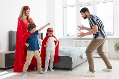 Photo of Parents and children in superhero costumes playing at home