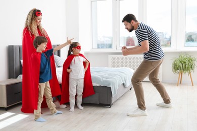 Photo of Parents and children in superhero costumes playing at home