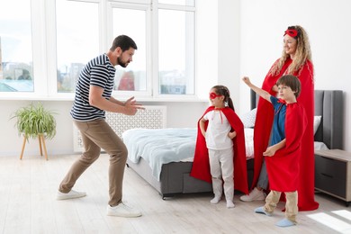 Photo of Parents and children in superhero costumes playing at home