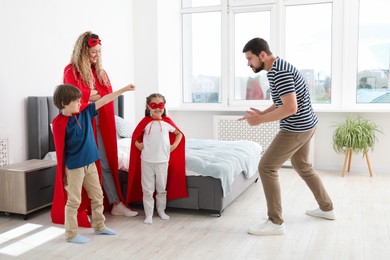 Photo of Parents and children in superhero costumes playing at home