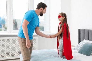 Photo of Father and his daughter in superhero costume playing at home